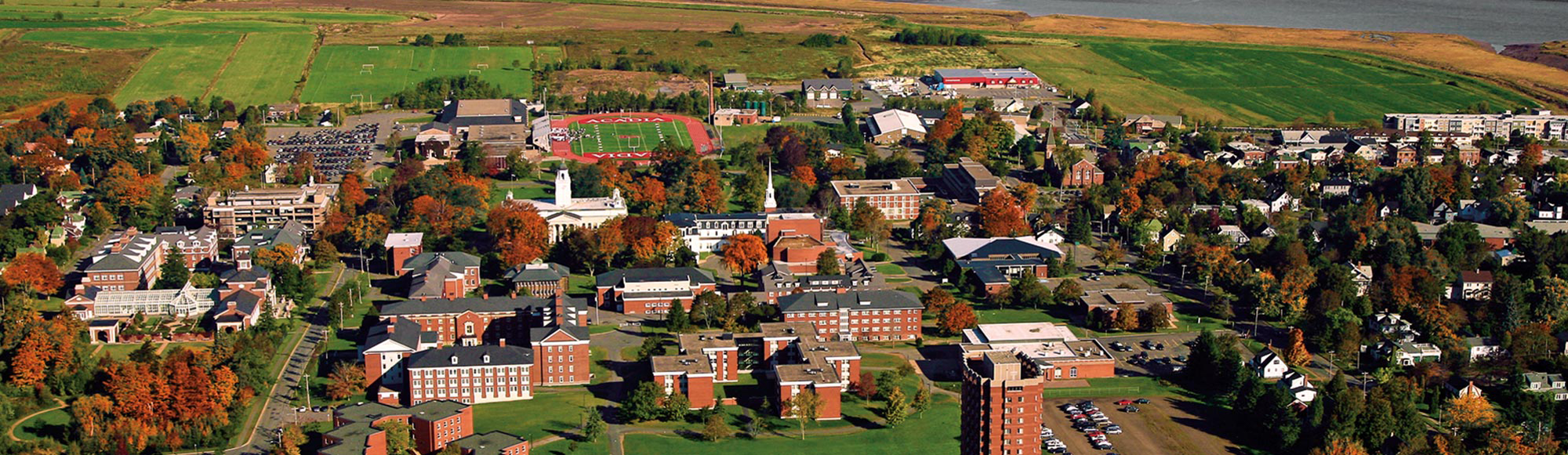 Acadia University sign in front of University Hall with large grass field and blue sky