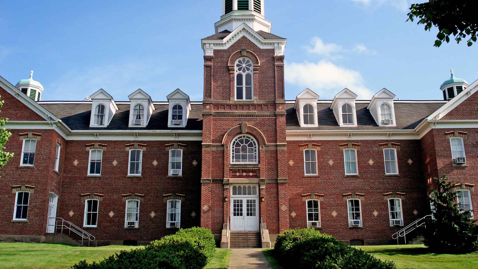 Red brick building with tower and walkway under blue skies on the St. Francis Xavier University campus